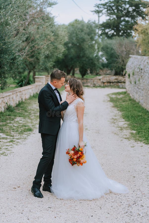 Happy stylish smiling couple walking in Tuscany, Italy on their wedding day. The bride and groom walk down the street by