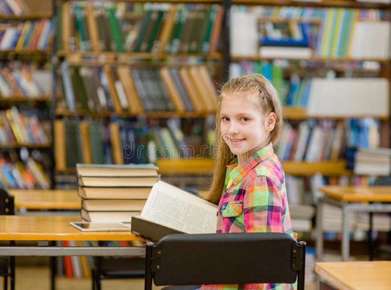 Happy teen girl with book look back in library