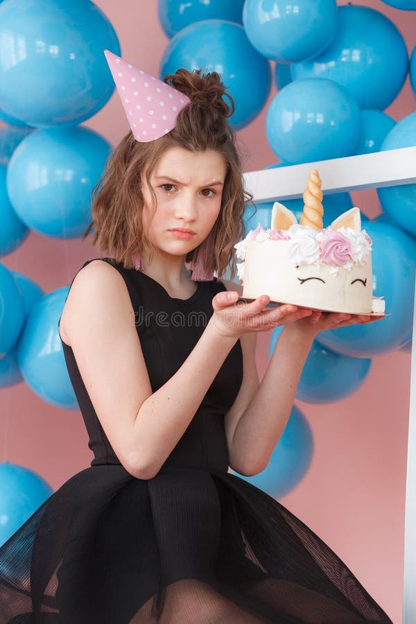 Happy teen girl holding unicorn layered cake decorated with meringues close-up. Pink background with blue balls royalty free stock photos Happy teen girl holding unicorn layered cake decorated with meringues close-up. Pink background with blue balls royalty free stock photos