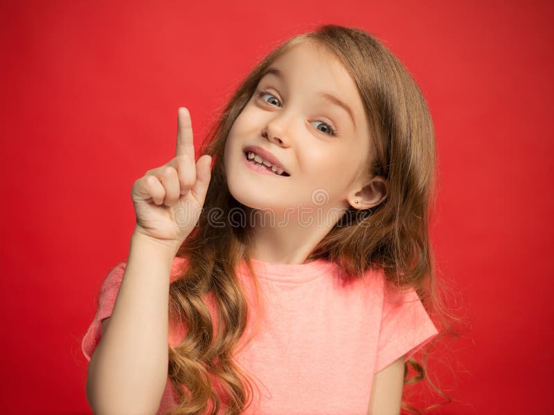 The happy teen girl standing and smiling against red background.