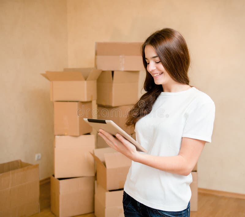 Happy teen girl with tablet computer standing on a background of boxes stock photo