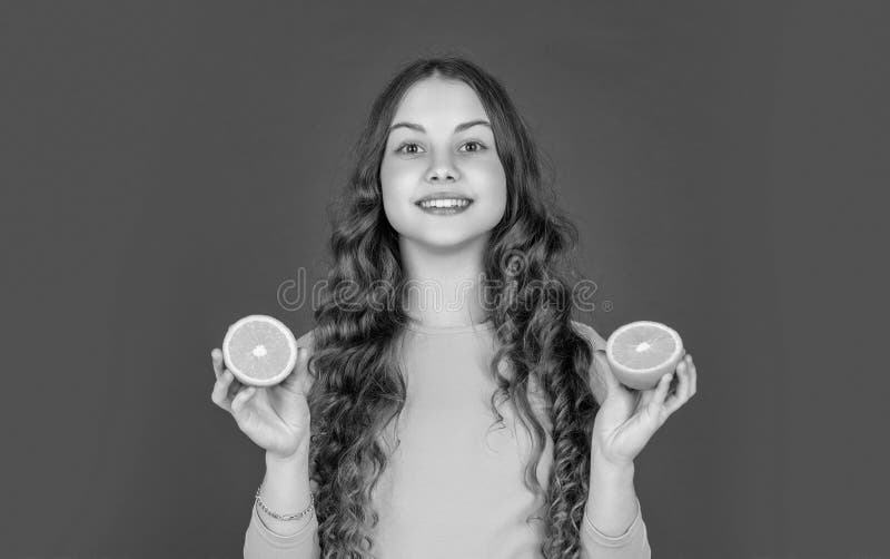 Happy Teen Kind halten orangefarbene Früchte auf violettem Hintergrund stockfoto