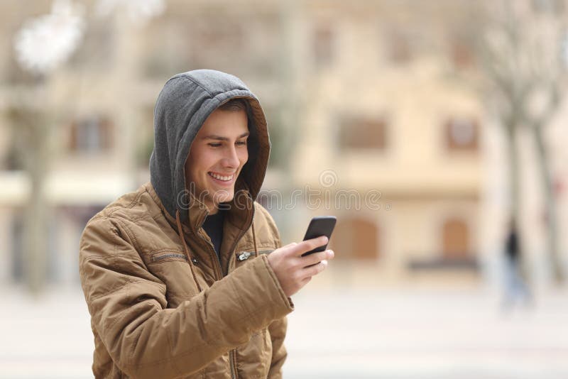 Happy teen boy walking on the street and using a smart phone. Happy teen boy walking on the street and using a smart phone