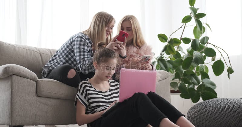 Teenage girls busy browsing social media on mobile phone and laptop