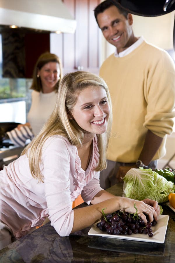 Happy teenage girl in kitchen with parents stock photography Happy teenage girl in kitchen with parents stock photography