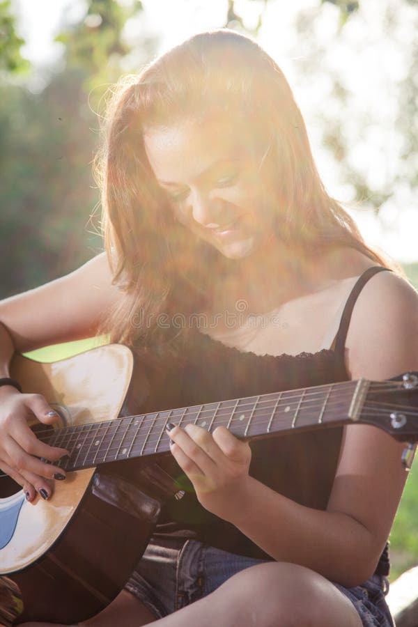 Happy teenage girl playing a guitar