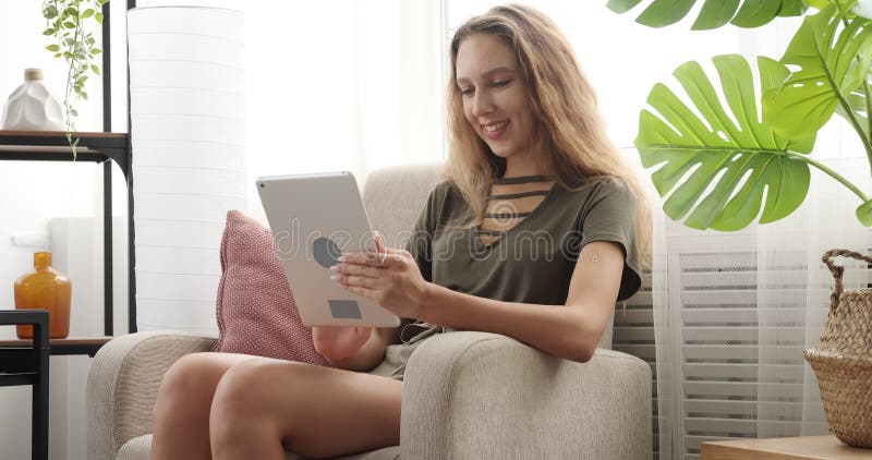 Happy teenage girl using digital tablet on armchair