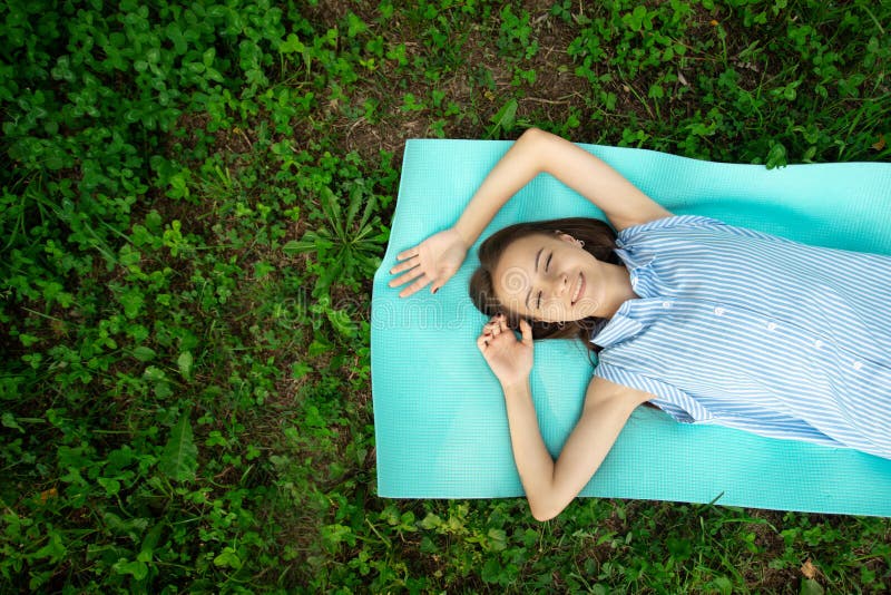 Happy teenager is lying on grass on sunny summer day,girl is resting in park,young beautiful woman in nature is smiling,rejoicing