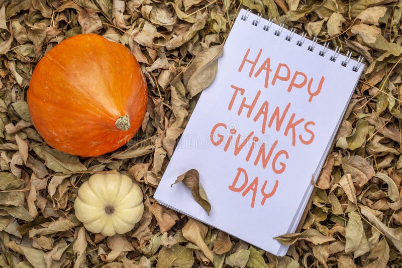 Happy Thanksgiving day - handwriting on a art sketchbook against dry fall leaves with squash and ornamental gourd. Happy Thanksgiving day - handwriting on a art sketchbook against dry fall leaves with squash and ornamental gourd