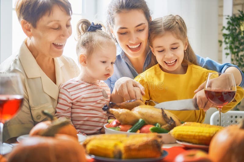 Happy Thanksgiving Day! Autumn feast. Family sitting at the table and celebrating holiday. Traditional dinner. Grandmother, mother and daughter.