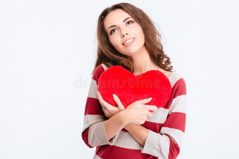 Portrait of a happy thoughtful woman holding red heart and looking up isolated on a white background