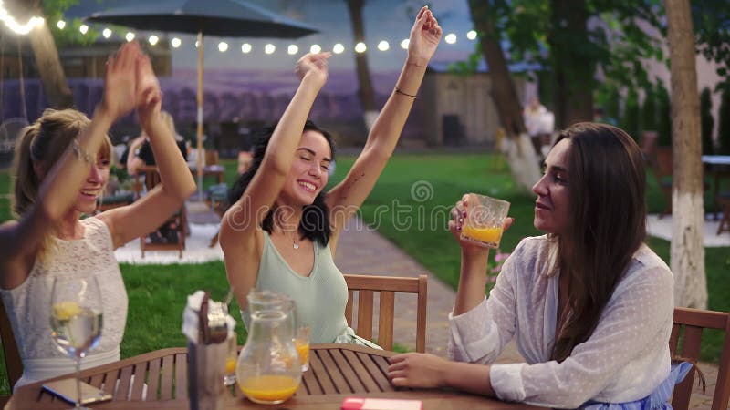 Happy, three attractive women having fun and dancing in the restaurant outdoors in the evening dusk stock video