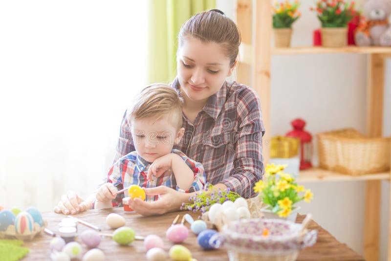 Happy time while painting easter eggs. Easter concept. Happy mother and her cute child getting ready for Easter by painting the eg stock photography Happy time while painting easter eggs. Easter concept. Happy mother and her cute child getting ready for Easter by painting the eg stock photography