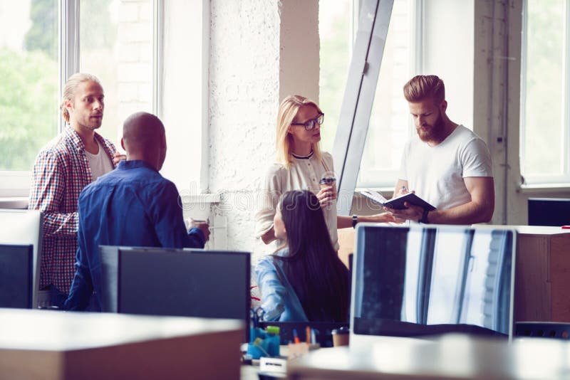Happy to work together. Group of young business people communicating while working in the office. royalty free stock photos Happy to work together. Group of young business people communicating while working in the office. royalty free stock photos