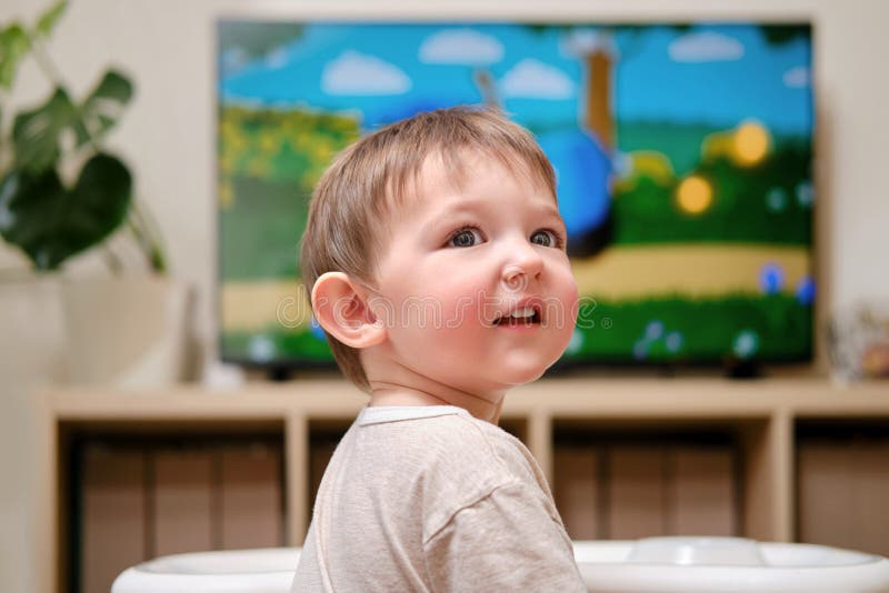 Happy Toddler Baby Boy Is Watching Cartoons On A Big Tv Screen A Chi