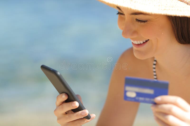 Happy tourist paying online with credit card on the beach. Happy tourist paying online with credit card and smart phone on the beach on summer vacation