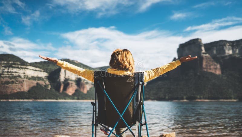Happy tourist traveler sits with raised hands, girl hiker enjoying mountains lake with arms outstretched breathing of fresh clean. Air in trip in spain royalty free stock image Happy tourist traveler sits with raised hands, girl hiker enjoying mountains lake with arms outstretched breathing of fresh clean. Air in trip in spain royalty free stock image