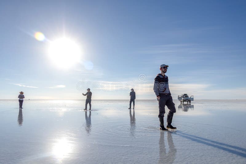 Happy tourists enjoy Jeep tour activities in Salt flat Lake Salar de Uyuni in Bolivia