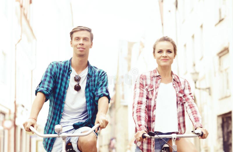 Happy Traveling Couple Riding On Bicycles. Boyfriend And Girlfriend In Old Town. Love, Relationship, Romance Concept.