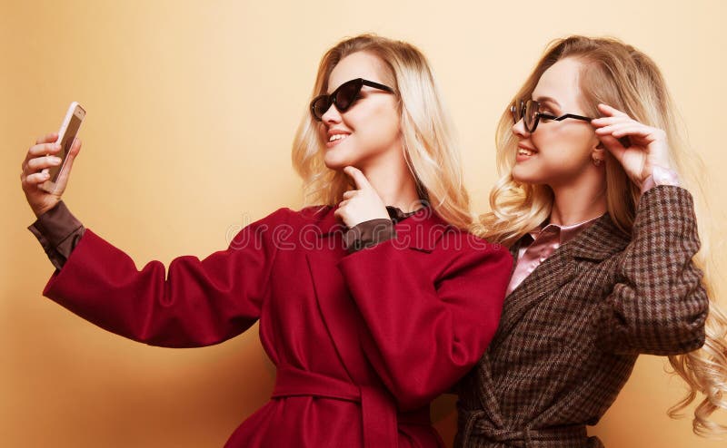 happy two smiling girls making selfie photo on smartphone on beige background royalty free stock photo happy two smiling girls making selfie photo on smartphone on beige background royalty free stock photo