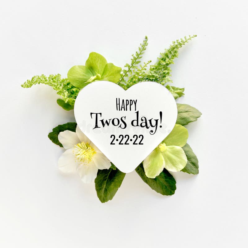 Happy Twos day 2.22.22 or Twosday. Winter flower arrangement. White paper heart with greeting text.