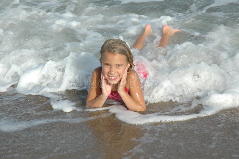 Una bella bambina di otto anni vecchia ragazza sorride da orecchio a orecchio durante la sua visita al oceano.