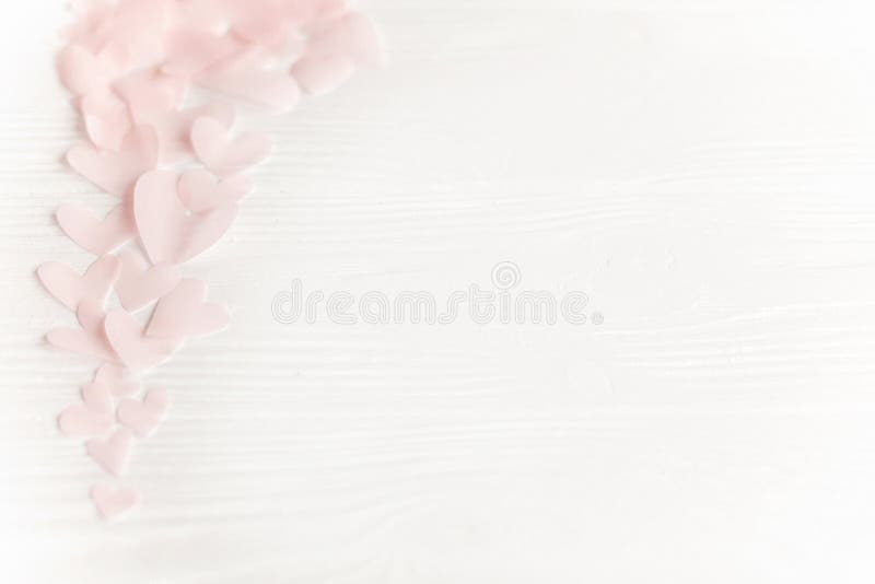 Happy valentines day. Cute pink pastel hearts on white wooden background with space for text.  Pink paper heart cutouts border on