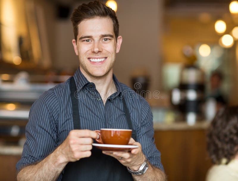 Happy Waiter Holding Coffee Cup In Cafeteria