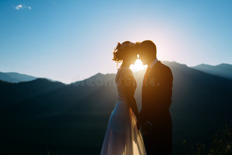 Happy wedding couple staying and kissing over the beautiful landscape with mountains stock photography Happy wedding couple staying and kissing over the beautiful landscape with mountains stock photography