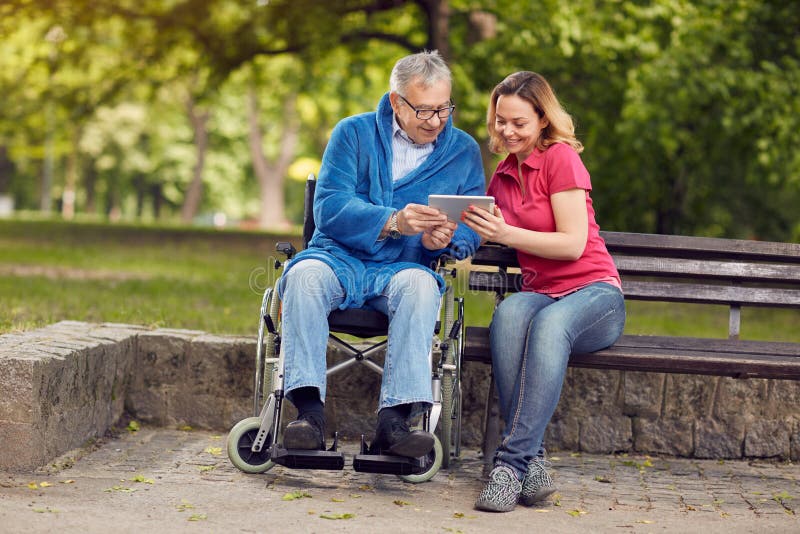 Happy wheelchair man with daughter using tablet stock photography