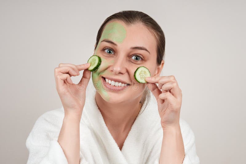 Happy Woman Applied A Face Mask With Cucumber Slices On Her Cheeks