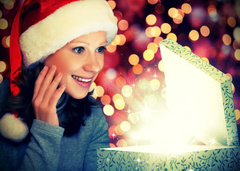 Happy woman in a Christmas cap opens the magic box stock photo