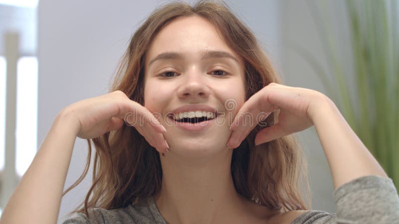 Happy Woman Doing Facial Massage By Hands And Looking In Bathroom