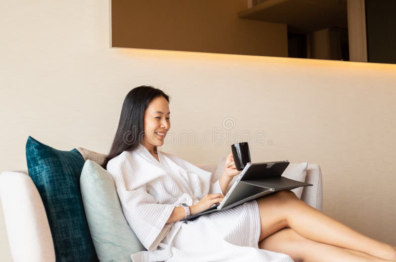 Happy woman in dressing gown sit on couch holding coffee working on laptop. Happy woman in dressing gown sit on couch holding coffee working on laptop