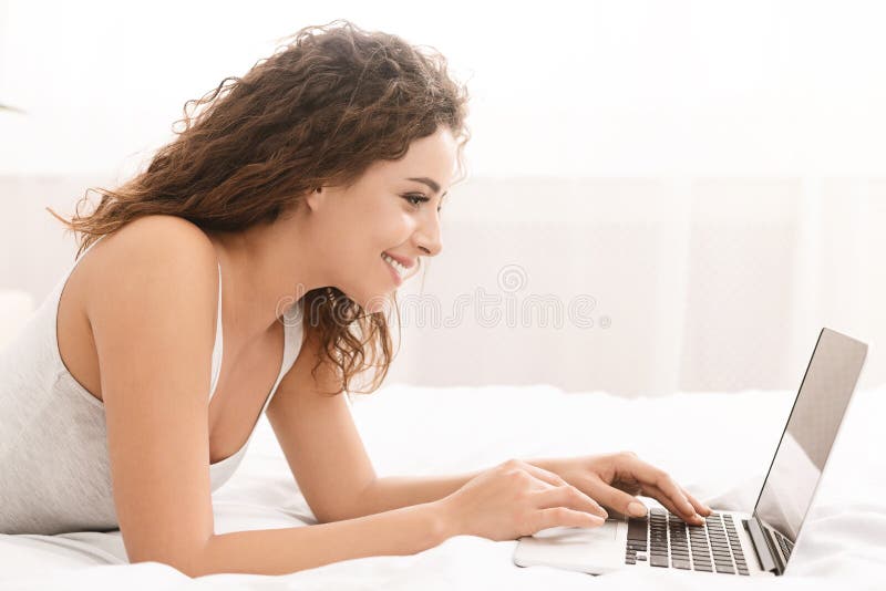 Happy woman flirting online on laptop in bed royalty free stock images Happy woman flirting online on laptop in bed royalty free stock images