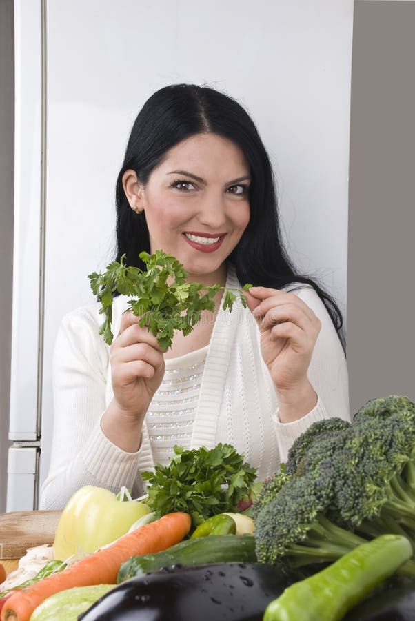 Happy woman with fresh parsley and vegetables