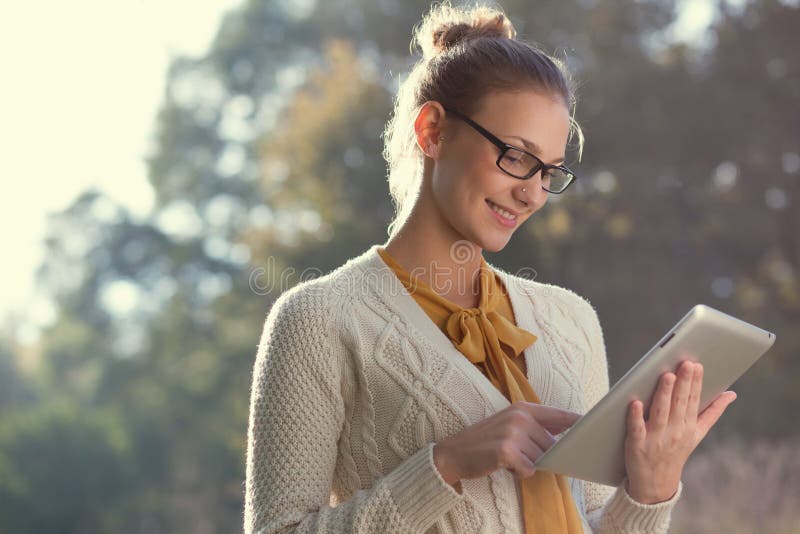 Detailní záběr na šťastná žena v brýlí pomocí počítače tablet pc v parku.