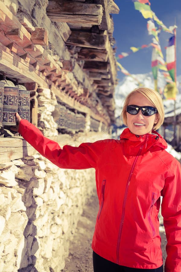 Happy woman hiker and prayer wheel in Nepal