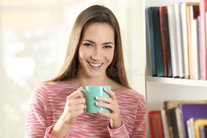 Happy woman holding a coffee cup looks at camera