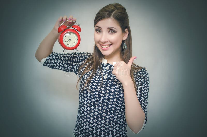 Happy girl with red alarm clock on gray background.
