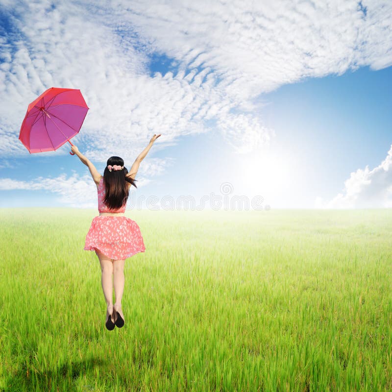 Happy Woman holding umbrella in green rice fields in sun sky