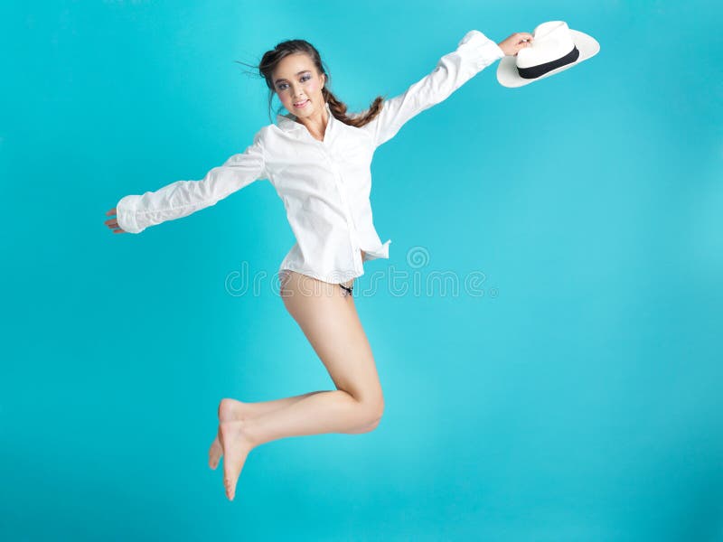 Happy woman jumping blue background white hat stock images