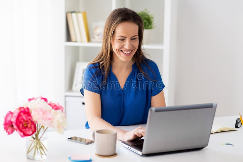Happy woman with laptop working at home or office stock photo