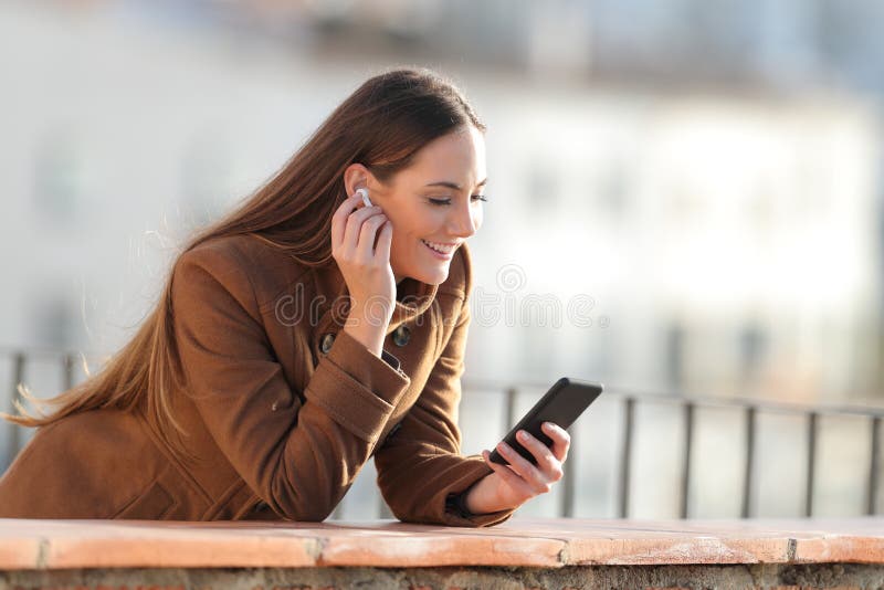Happy woman listening to music putting earbuds stock image Happy woman listening to music putting earbuds stock image