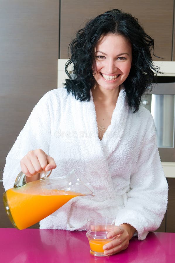 Happy woman with orange juice at domestic kitchen