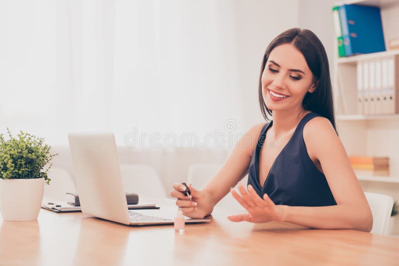 Happy woman painting nails instead of working in office