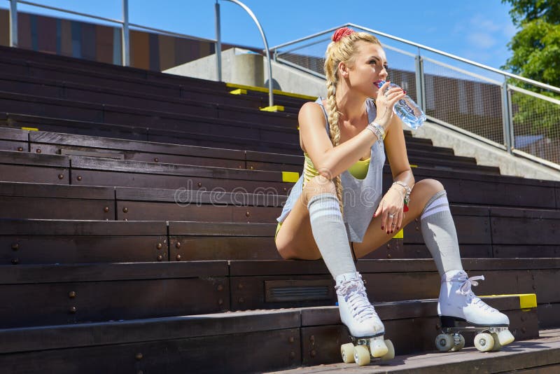 Happy woman posing in a vintage roller skates, T-shirt, shorts posing on a road in city  hot summer day. Holidays and vacations