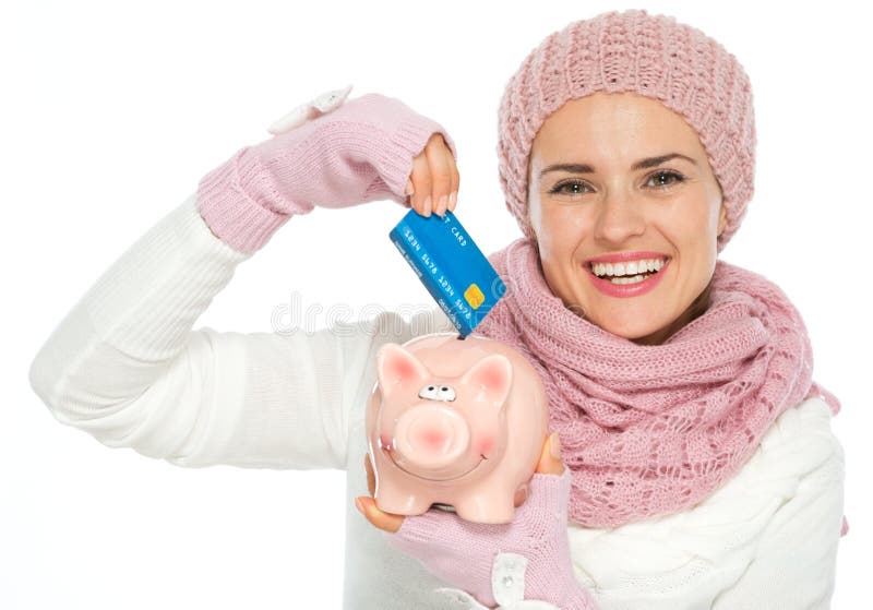 Happy woman putting credit card in piggy bank