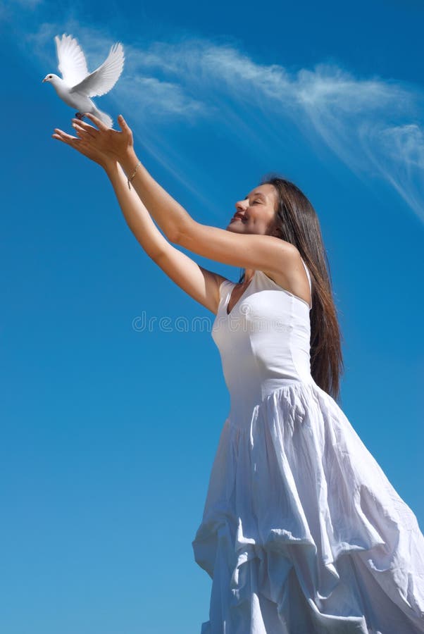 Happy woman releasing a pigeon in sky. The happy woman releasing a pigeon in sky stock image