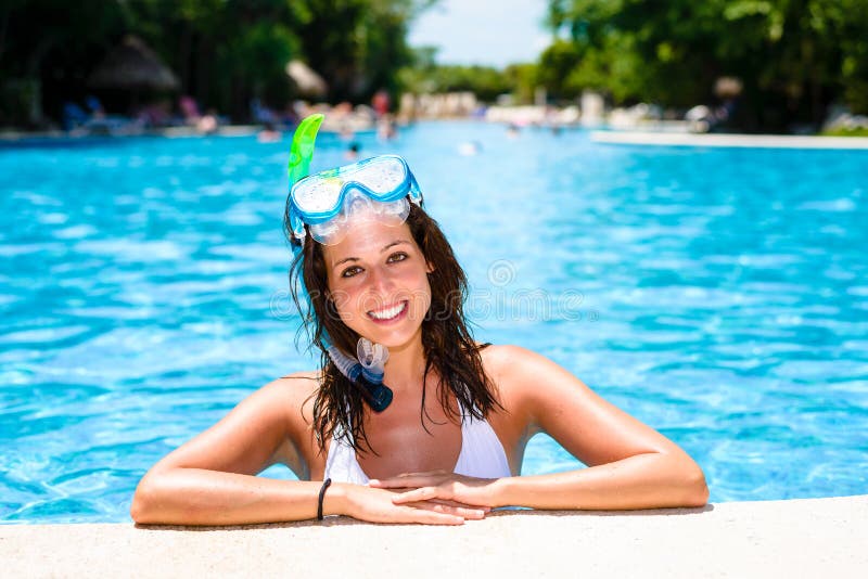Happy woman with snorkel gear swimming in tropical resort pool and enjoying relaxing vacation. Happy woman with snorkel gear swimming in tropical resort pool and enjoying relaxing vacation.